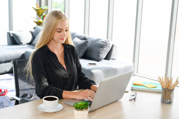"A professional insurance agent working on a laptop, having a video call with a client in a home office setup."