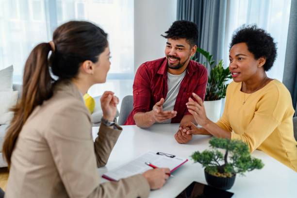 An insurance agent represents a couple with policy documents, explaining details and benefits of their new life insurance policy.