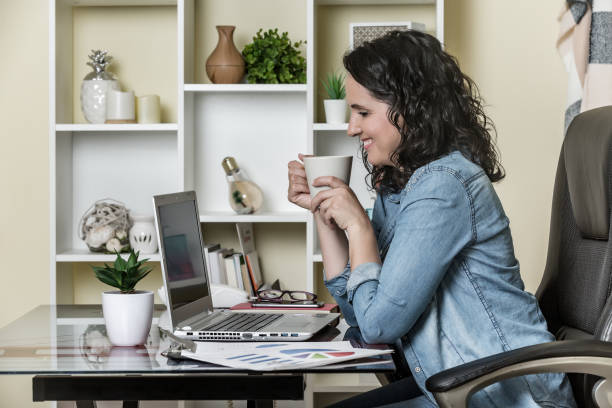 "Smiling remote insurance agent working on laptop from their home office, representing the benefits of working remotely in the insurance industry."