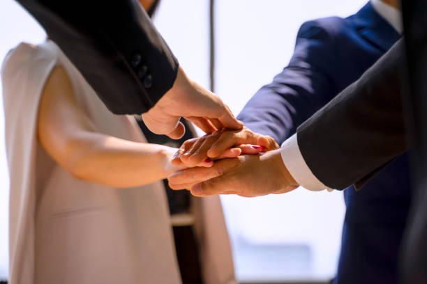 Image of a business woman joining hands with a group of executives in business suits.