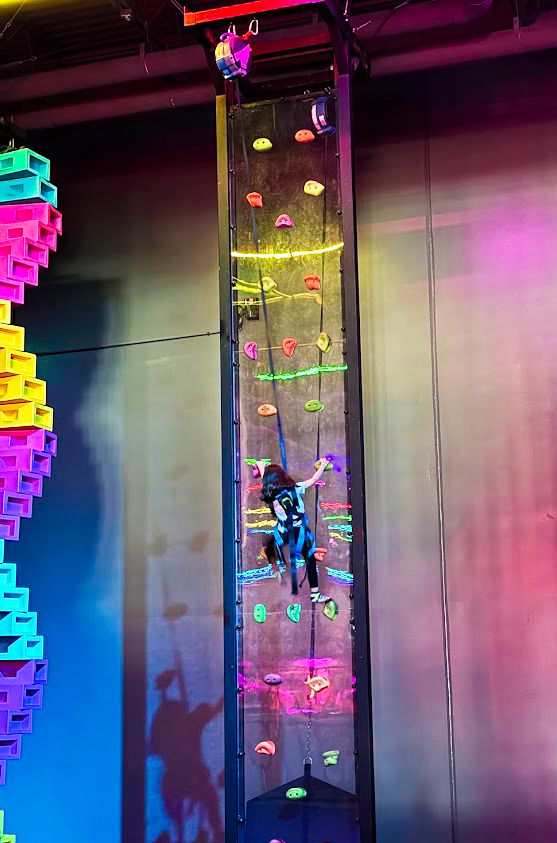 A girl going up a climbing wall at Urban Air A girl going up a climbing wall at Urban Air