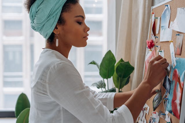 A woman pinning images on a cork board A woman pinning images on a cork board