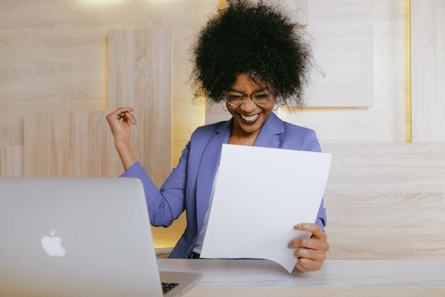 Woman smiling while holding a paper Woman smiling while holding a paper