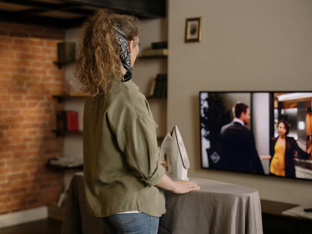 Woman ironing clothes while watching television Woman ironing clothes while watching television