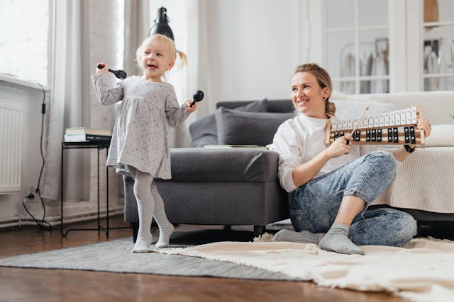 Girl dancing while holding maracas and mother playing xylophone