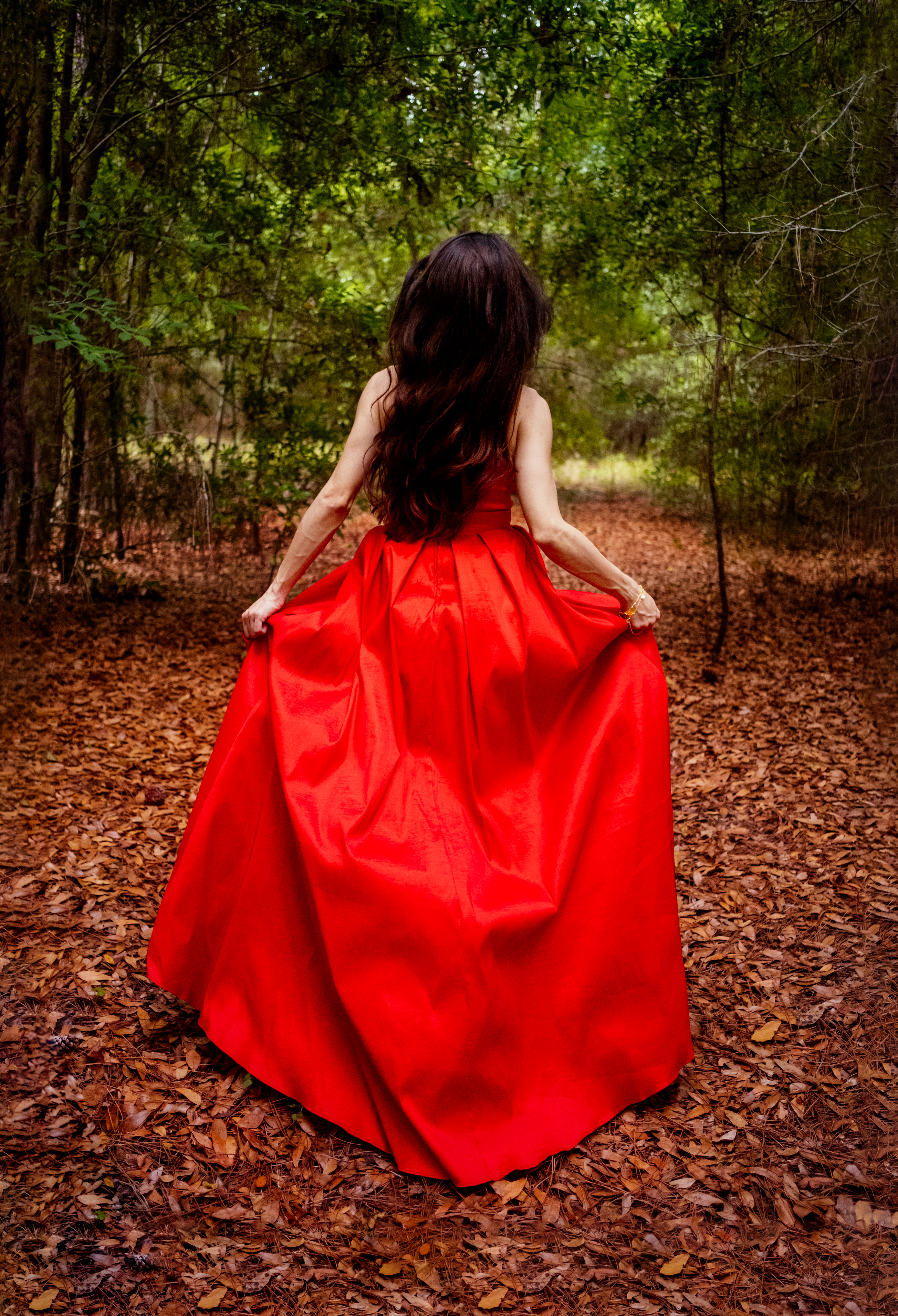 A woman running in the woods in a red dress