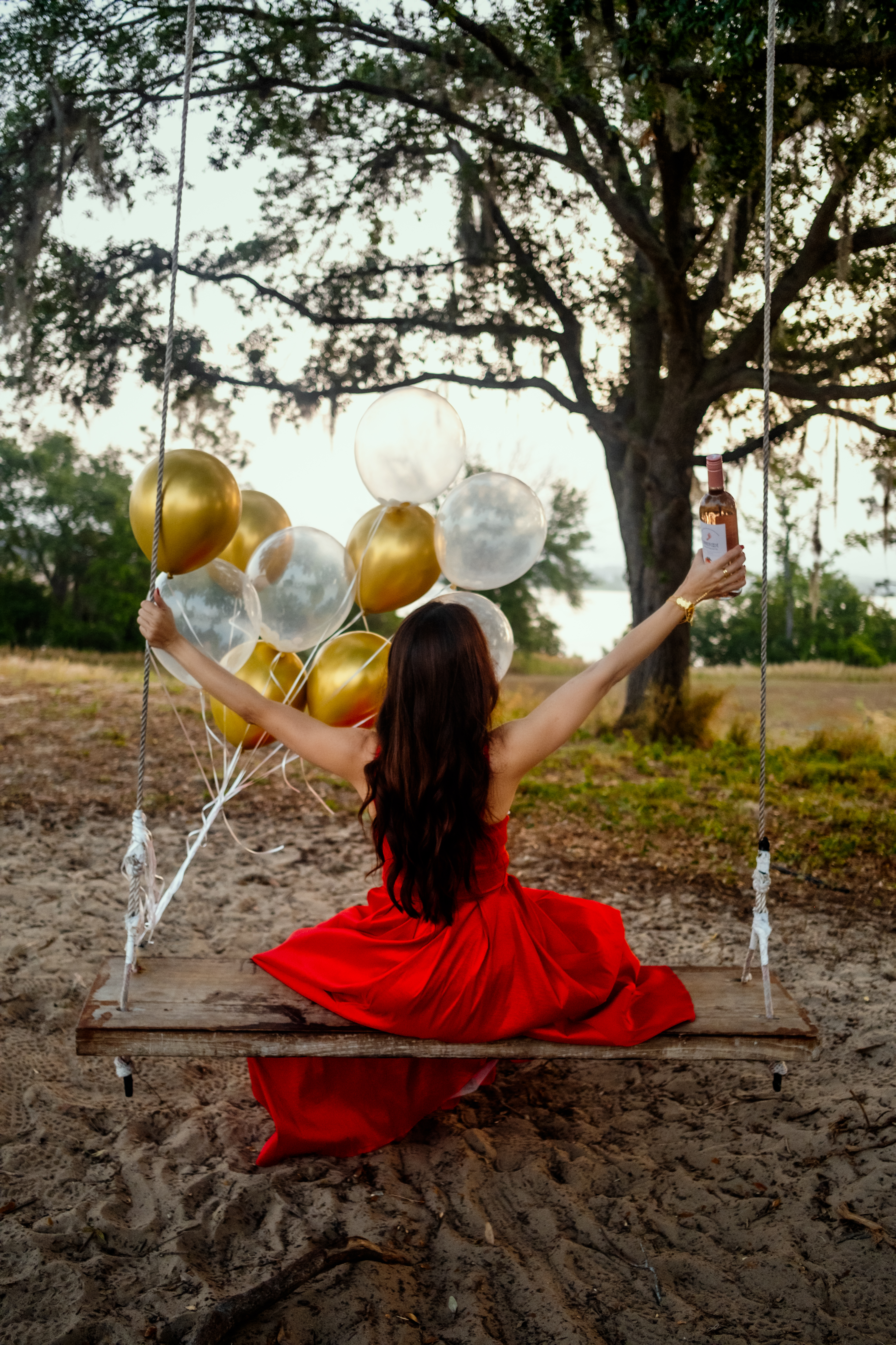A woman in a red dress on a wooden swing in a park A woman in a red dress on a wooden swing in a park
