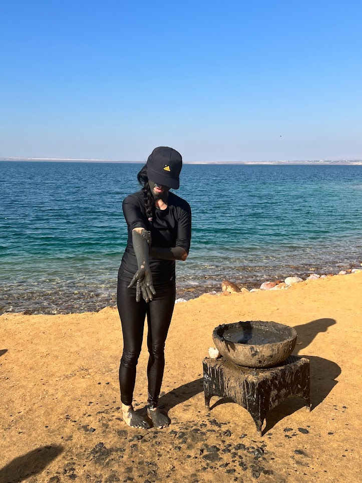 Woman putting mud on her face and body