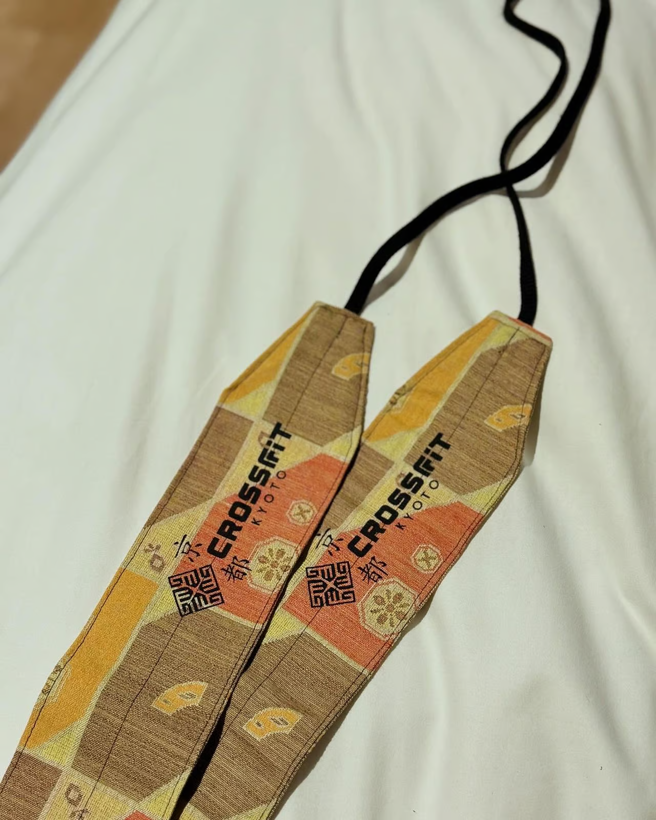 pair of custom-designed lifting straps with 'CrossFit Kyoto' branding, placed on a white surface. pair of custom-designed lifting straps with 'CrossFit Kyoto' branding, placed on a white surface.