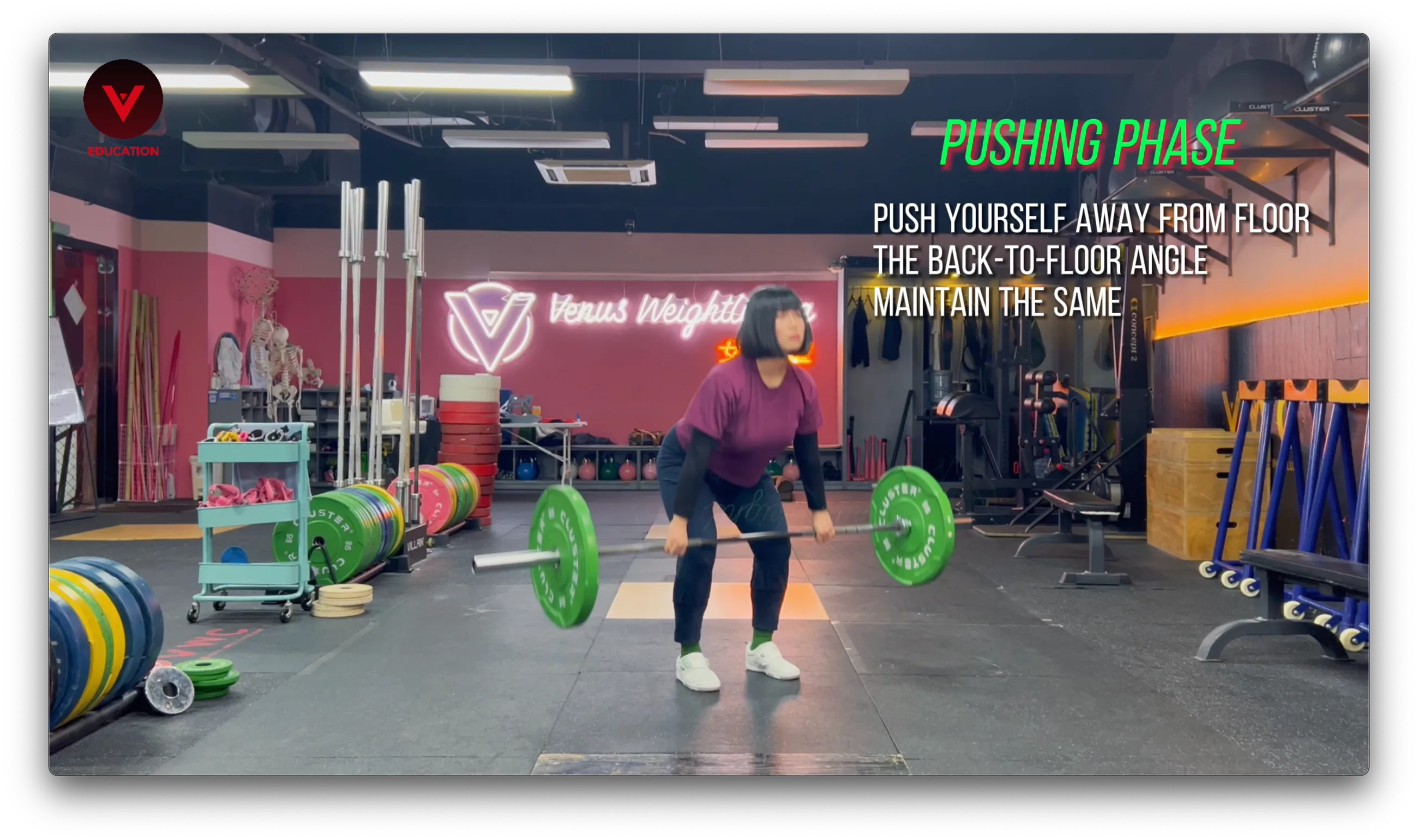 Weightlifting coach demonstrating the pushing phase of the clean at Venus Weightlifting gym, with instructions to push away from the floor while maintaining the back-to-floor angle Weightlifting coach demonstrating the pushing phase of the clean at Venus Weightlifting gym, with instructions to push away from the floor while maintaining the back-to-floor angle