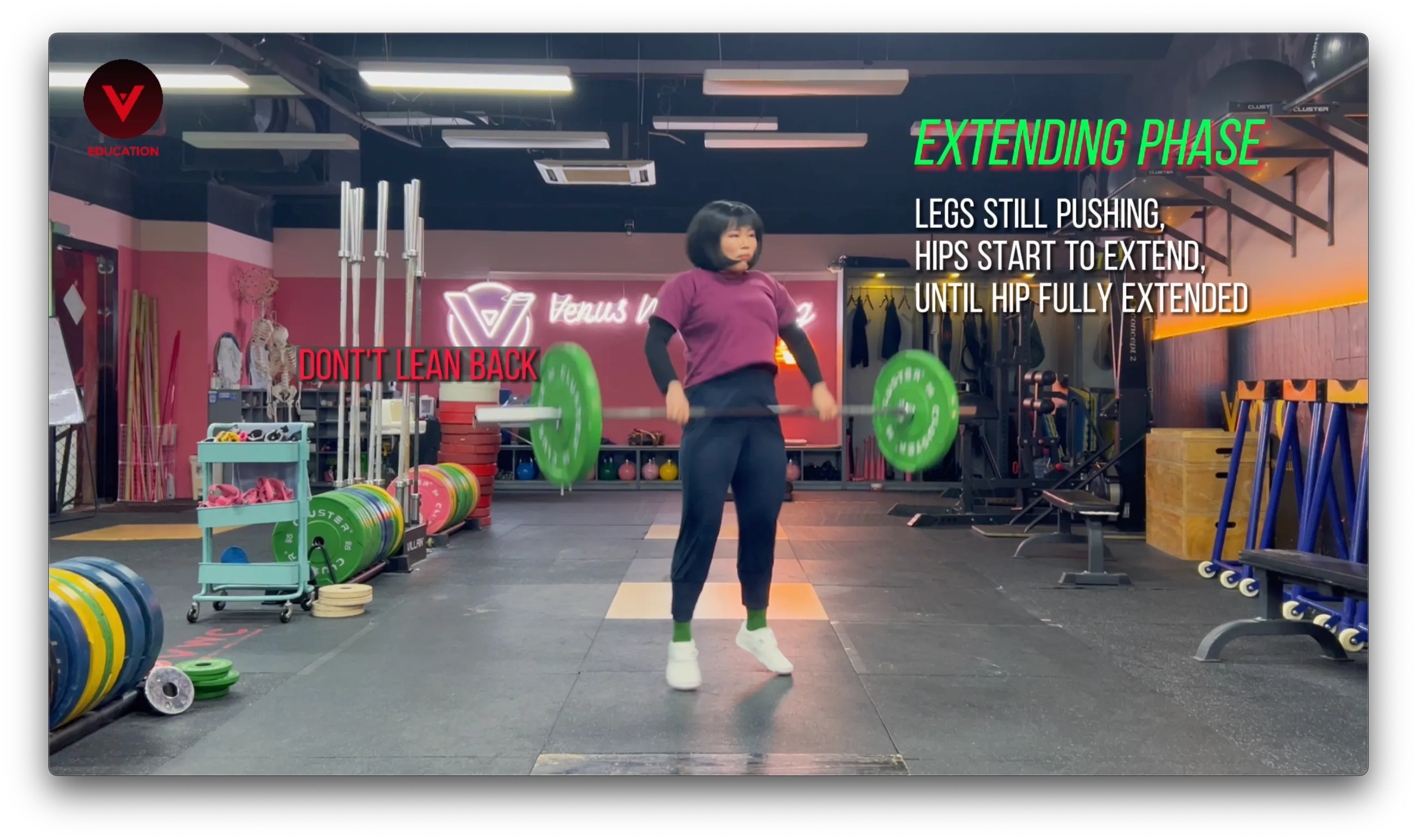 Weightlifting coach demonstrating the extending phase of the clean at Venus Weightlifting gym, highlighting proper hip extension while emphasizing not to lean back during the movement. Weightlifting coach demonstrating the extending phase of the clean at Venus Weightlifting gym, highlighting proper hip extension while emphasizing not to lean back during the movement.