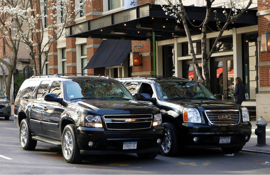Black Chevrolet Suburban and GMC Yukon SUVs parked on a city street, showcasing luxury and executive transportation. Black Chevrolet Suburban and GMC Yukon SUVs parked on a city street, showcasing luxury and executive transportation.