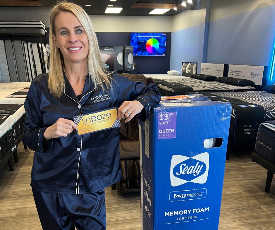 Annette Janssen, a Sleep Coach, stands with one of the five mattresses given away for $5 at the grand opening celebration in Omaha, NE.