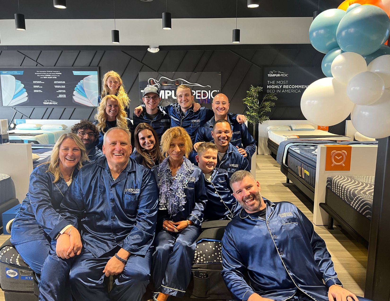 Snooze Mattress Co. staff pose on a mattress in the Parker, CO store. 