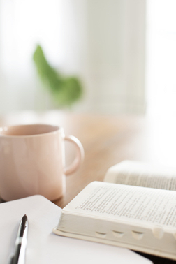 Bible opened with coffee cup nearby Bible opened with coffee cup nearby