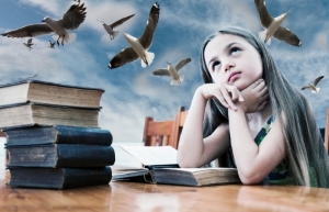 young girl daydreaming over old books with birds flying above in a blue sky