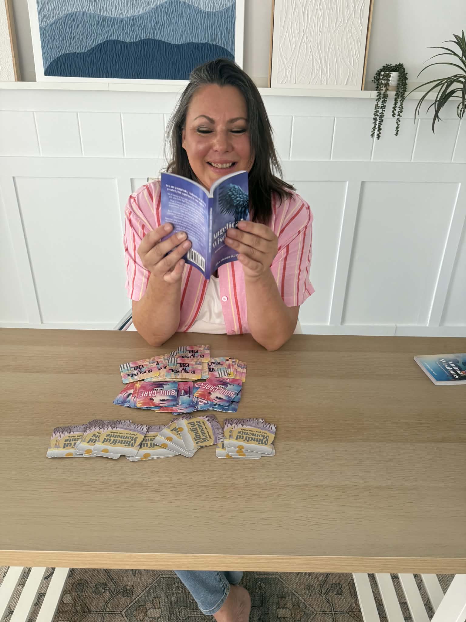 Julia Van Der Sluys holding Angelical Wisdoms with Affirmation Decks on the table