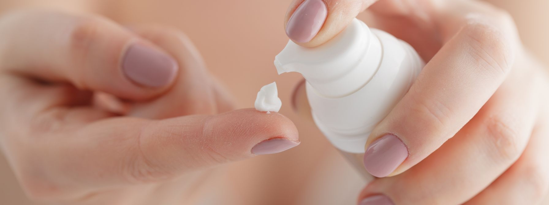 Close-up of a person dispensing a small amount of moisturizer onto their fingertip, illustrating an essential step in post-dermaplaning skincare for hydration and recovery. Close-up of a person dispensing a small amount of moisturizer onto their fingertip, illustrating an essential step in post-dermaplaning skincare for hydration and recovery.