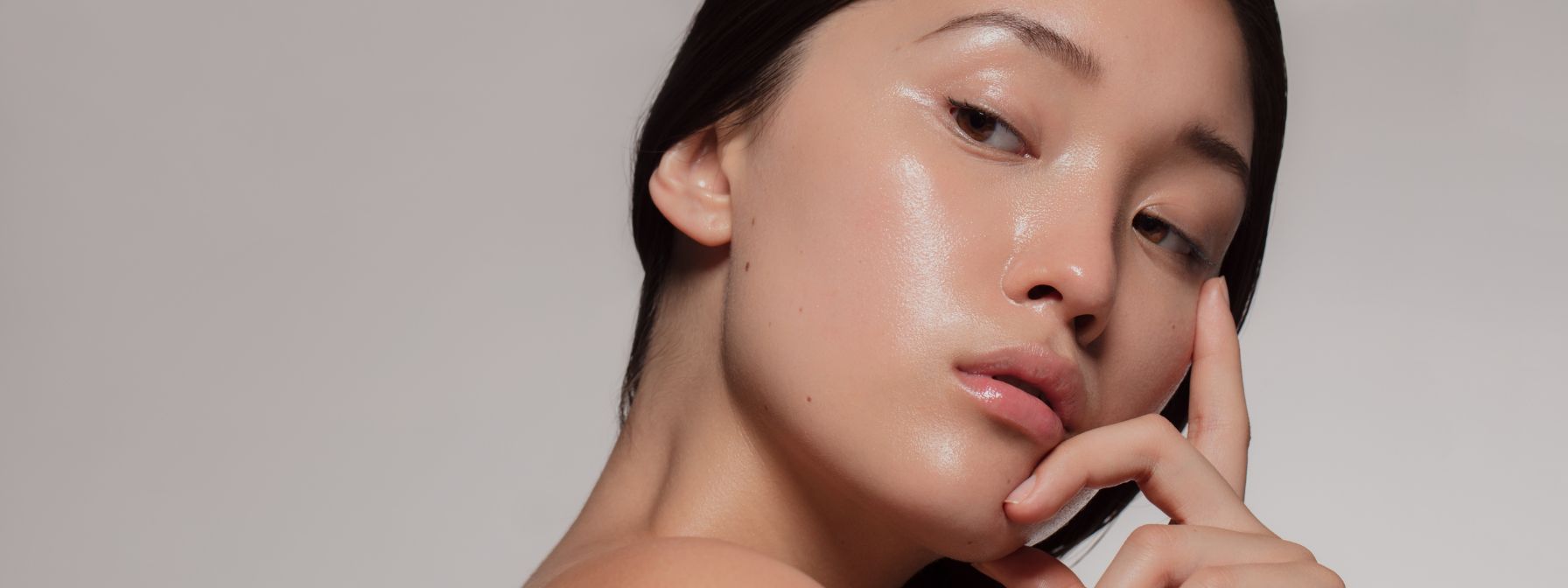 Close-up of a woman with flawless, dewy skin gently touching her face, highlighting a smooth and radiant complexion ideal for showcasing skincare results. Close-up of a woman with flawless, dewy skin gently touching her face, highlighting a smooth and radiant complexion ideal for showcasing skincare results.