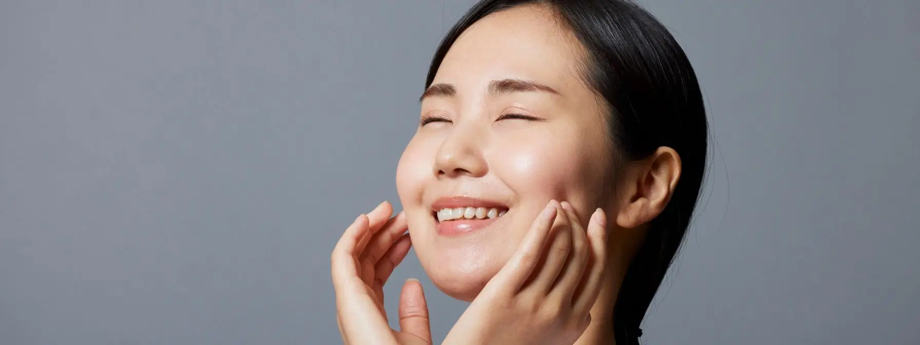 Smiling woman gently touching her radiant, smooth skin with closed eyes—showcasing the refreshed and glowing results of chemical peel treatments in Greenville, SC.