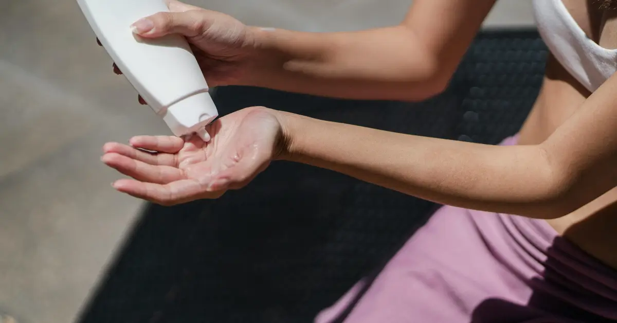 Close-up of a woman applying sunscreen from a white bottle onto her hand Close-up of a woman applying sunscreen from a white bottle onto her hand