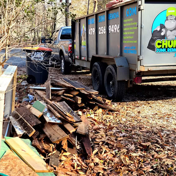 Chums Junk Removal truck and trailer hauling away old wood debris and junk from a residential property in Northwest Arkansas. Chums Junk Removal truck and trailer hauling away old wood debris and junk from a residential property in Northwest Arkansas.