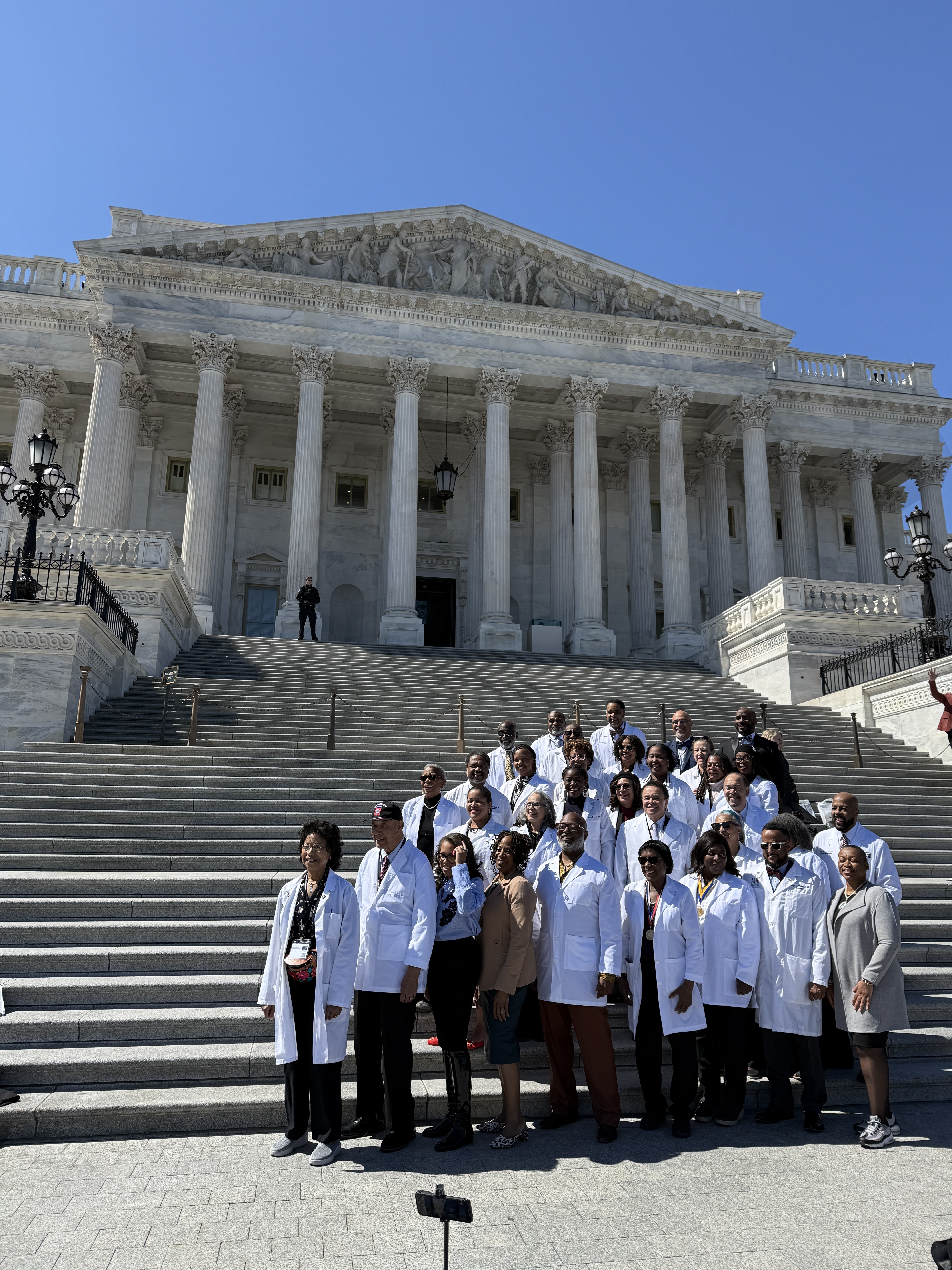 Group of physicians in white coats gathered on the steps of the U.S. Capitol during the NMA Colloquium Hill Day, symbolizing advocacy and the collective voice of Black physicians in healthcare policy.