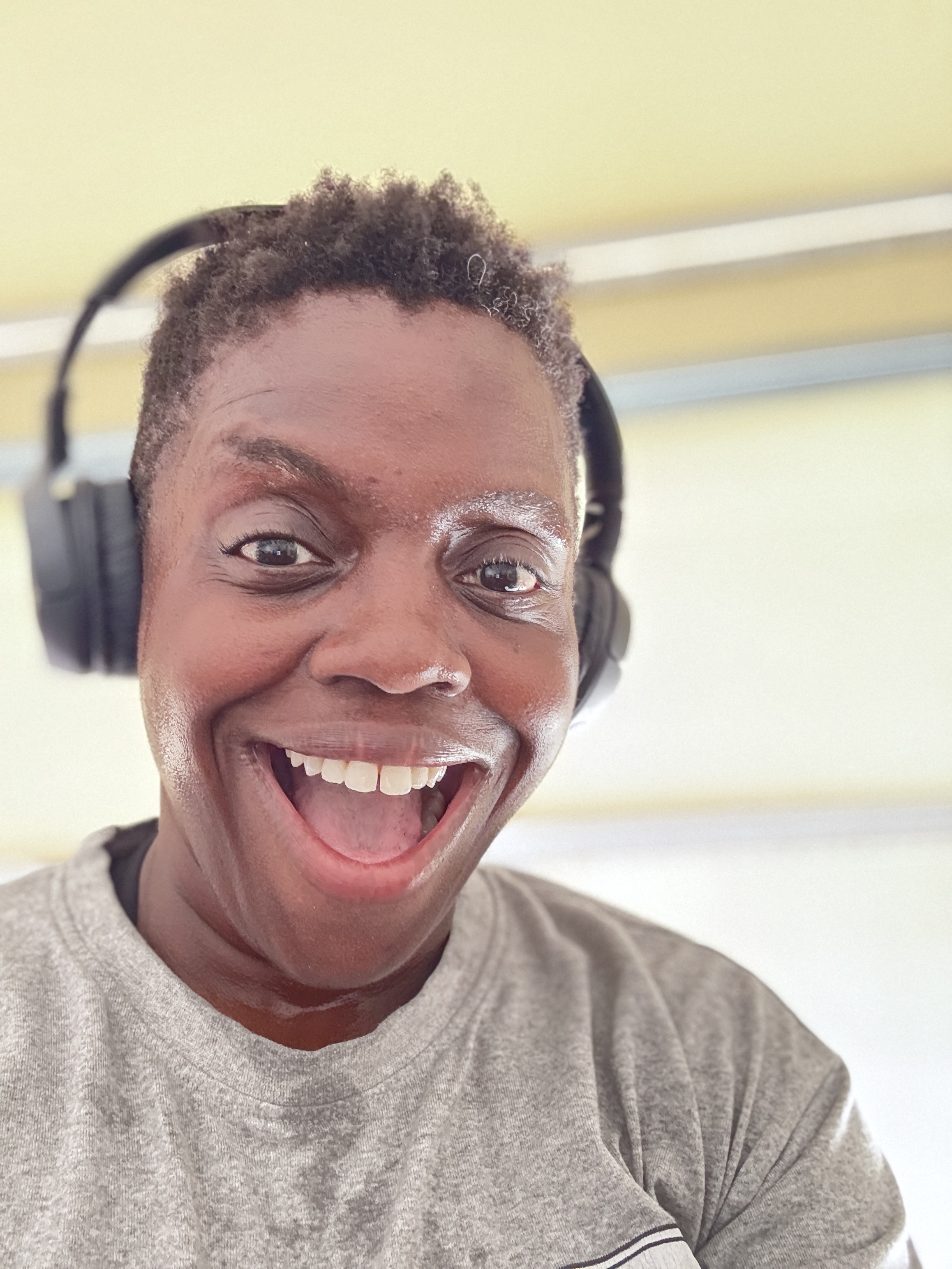 Rafat Fields smiles widely after a workout, wearing headphones and a gray T-shirt. The photo captures her joyful, energetic expression as part of her ongoing health and fitness journey. Rafat Fields smiles widely after a workout, wearing headphones and a gray T-shirt. The photo captures her joyful, energetic expression as part of her ongoing health and fitness journey.