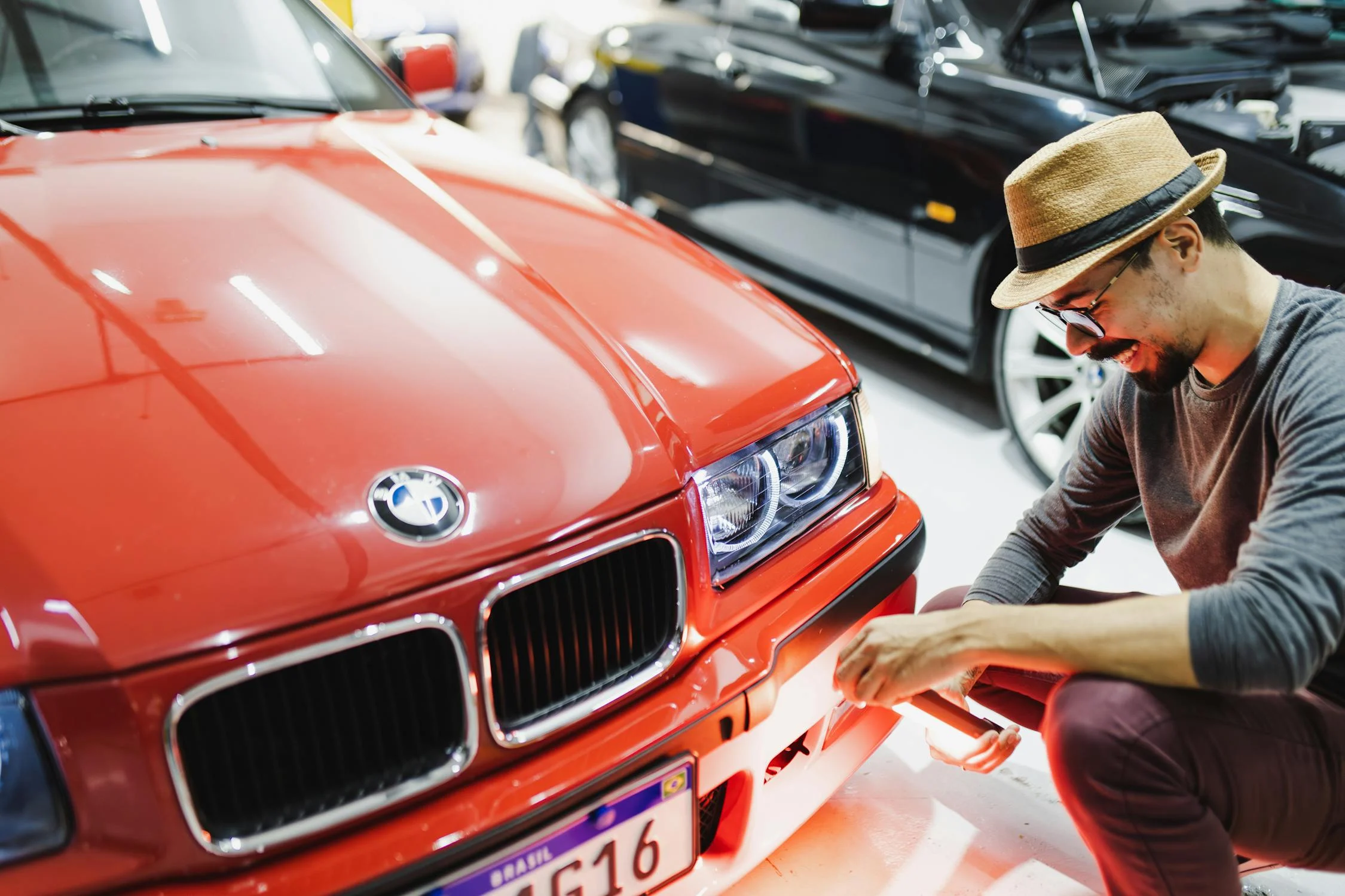 Detail technician performing finish inspection on red luxury car in Houston auto detail shop