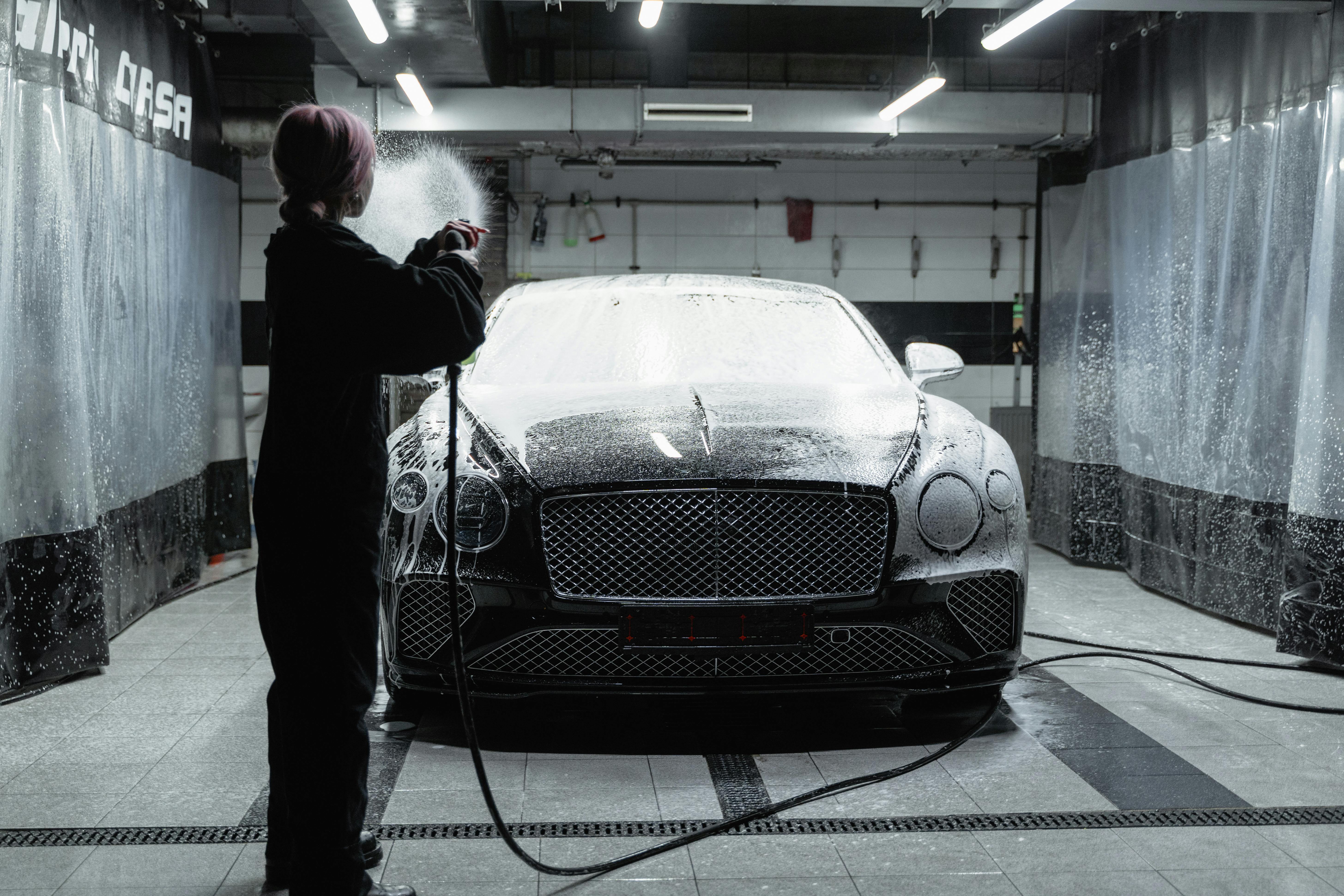 Luxury black car receiving mobile detailing foam treatment in Houston garage