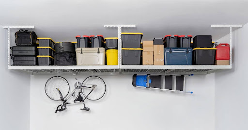 A neatly organized garage with overhead metal shelving holding plastic storage bins, cardboard boxes, and a red gas can. A bicycle is mounted on the wall, and a foldable ladder is stored securely alongside it, maximizing floor space. A neatly organized garage with overhead metal shelving holding plastic storage bins, cardboard boxes, and a red gas can. A bicycle is mounted on the wall, and a foldable ladder is stored securely alongside it, maximizing floor space.