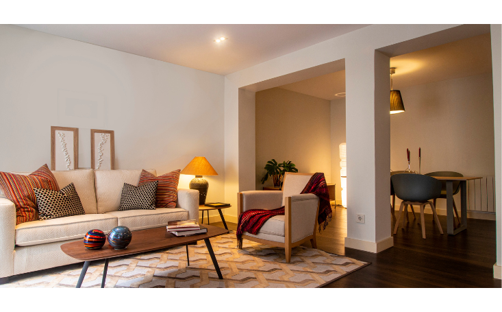 An inviting and tidy living room with minimalistic decor, featuring a neatly organized bookshelf, a clear coffee table, and comfortable seating bathed in natural light, illustrating a decluttered and serene home environment.