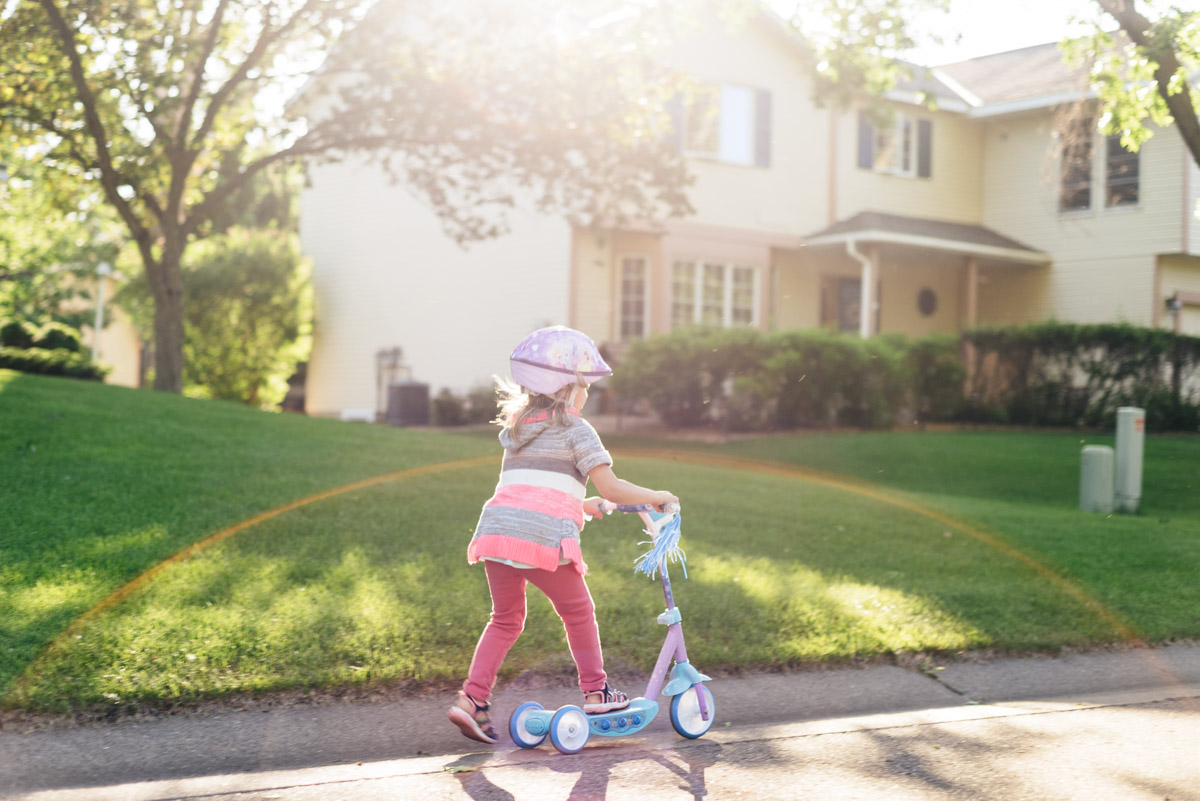 Woodbury family videography session. Young girl rides her scooter down the road.