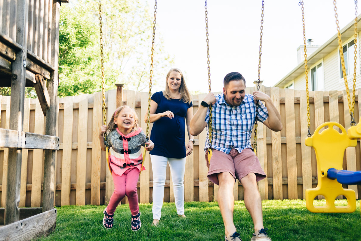 Father and daughter on swing while mother pushes during Woodbury family videography session.