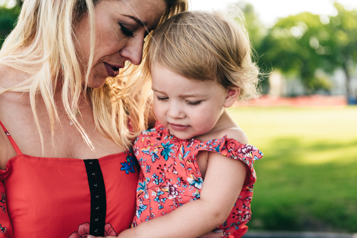 Mother holds daughter outside.