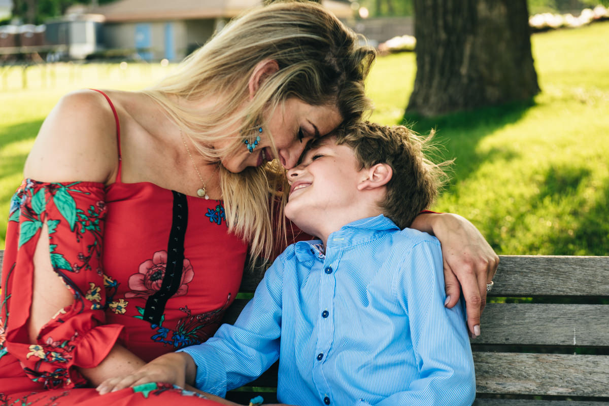 Excelsior, MN, family photography. Mother and son with heads together laughing on bench.