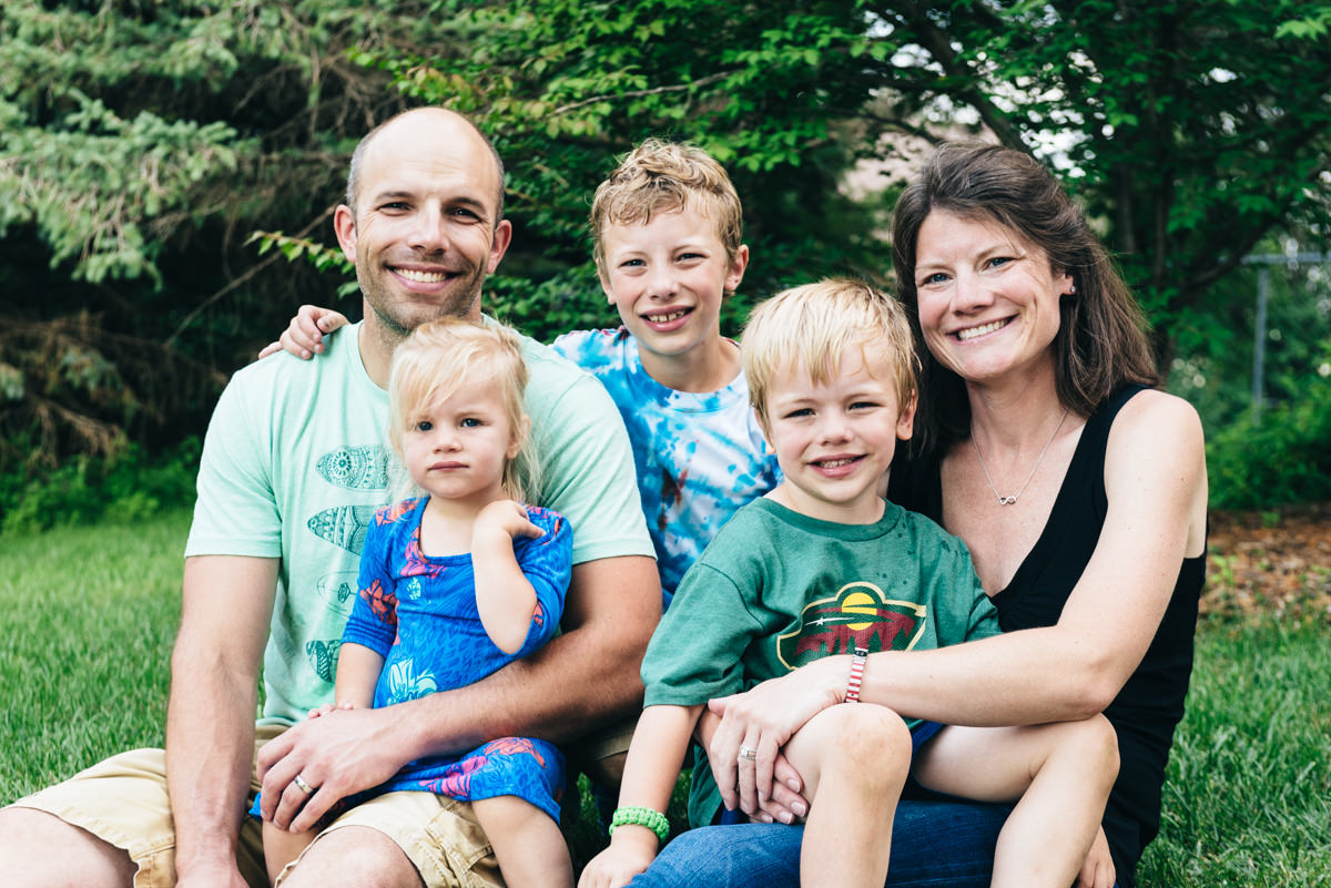 A family of five posing near trees. Military homecoming surprise video.