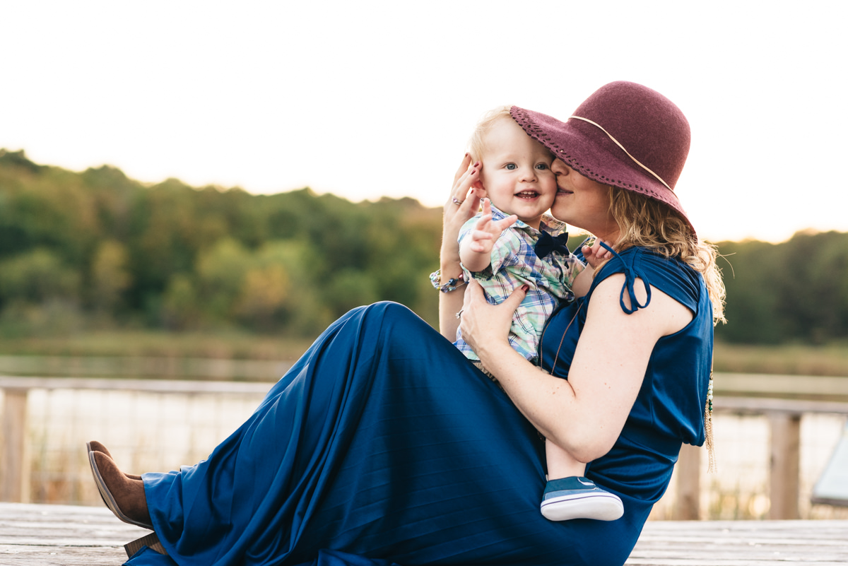 Mother kisses son on the cheek while she holds him during sunset session.