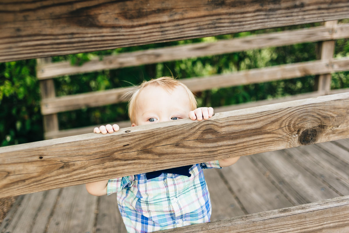 Little boy peers over the ledge of a bridge.