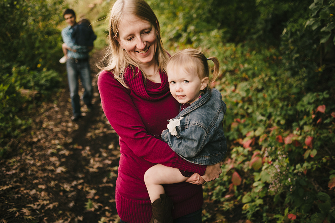 Mom carries daughter down path through woods.