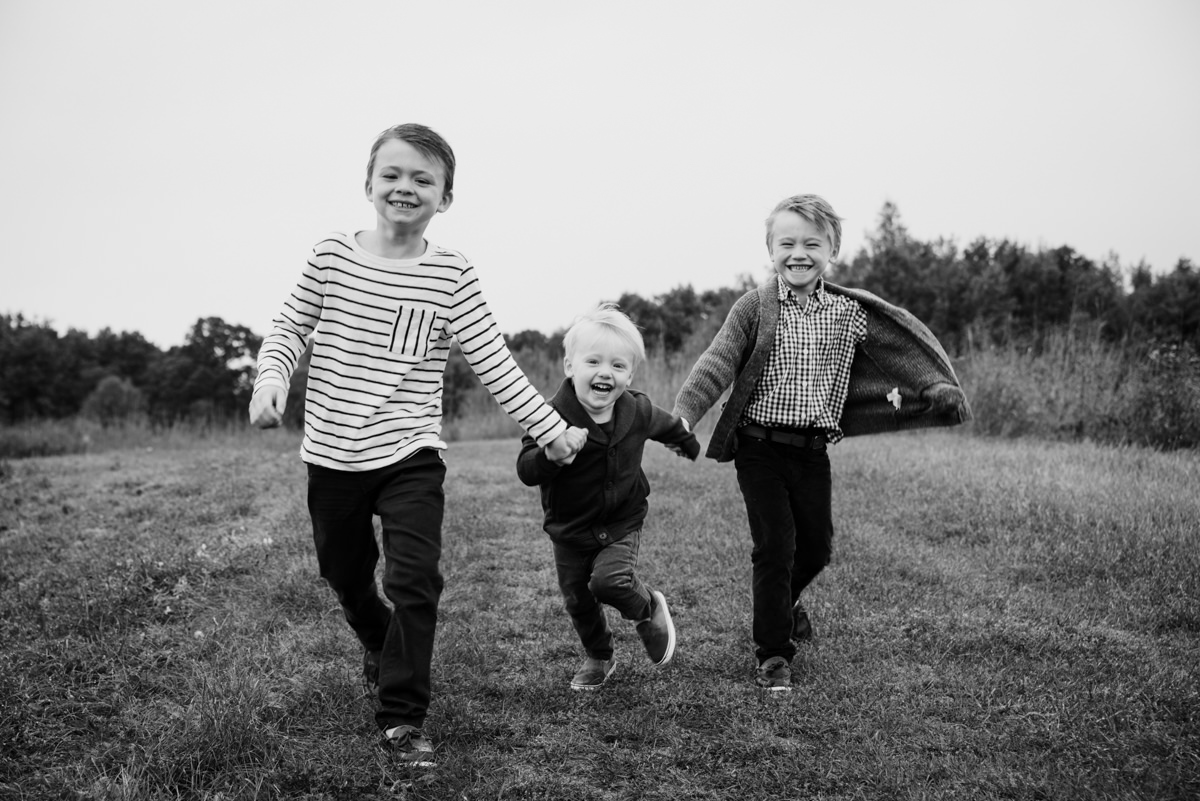 Three brothers hold hands and run. Lake Elmo Park photography.