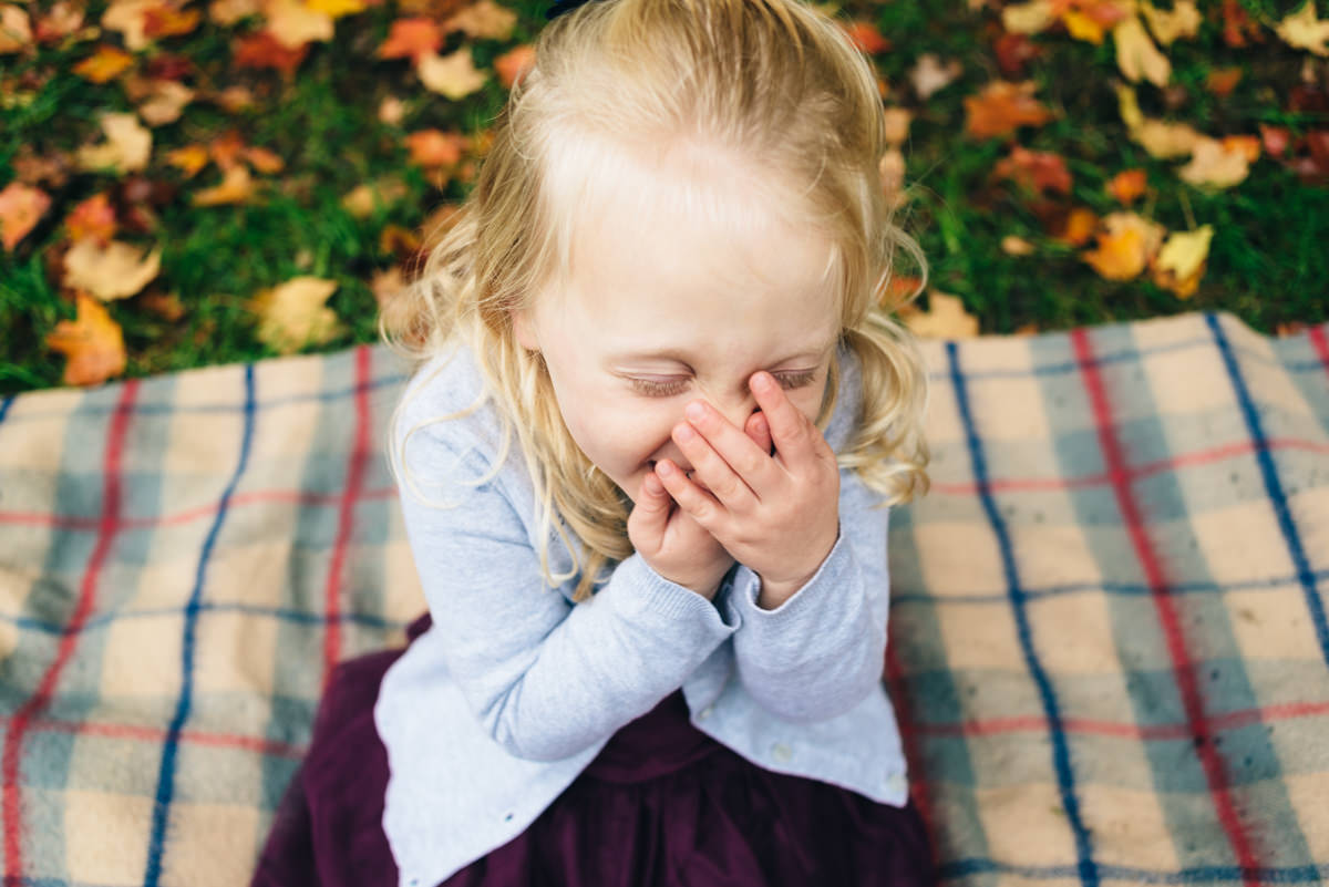 Little girl holds hand to mouth as she laughs.