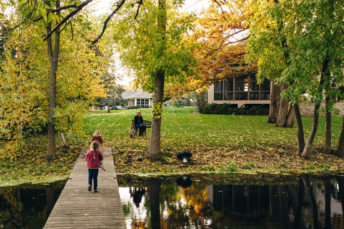 Two little girls walk down dock in Edina MN photo session. Photo taken from behind them.