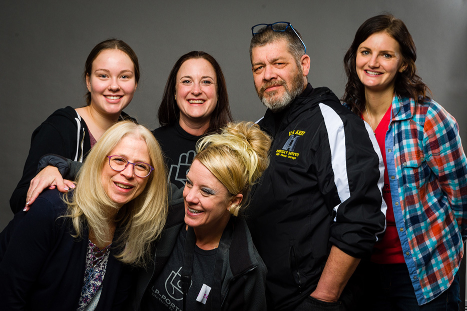 Volunteers pose for a photo against a grey backdrop.