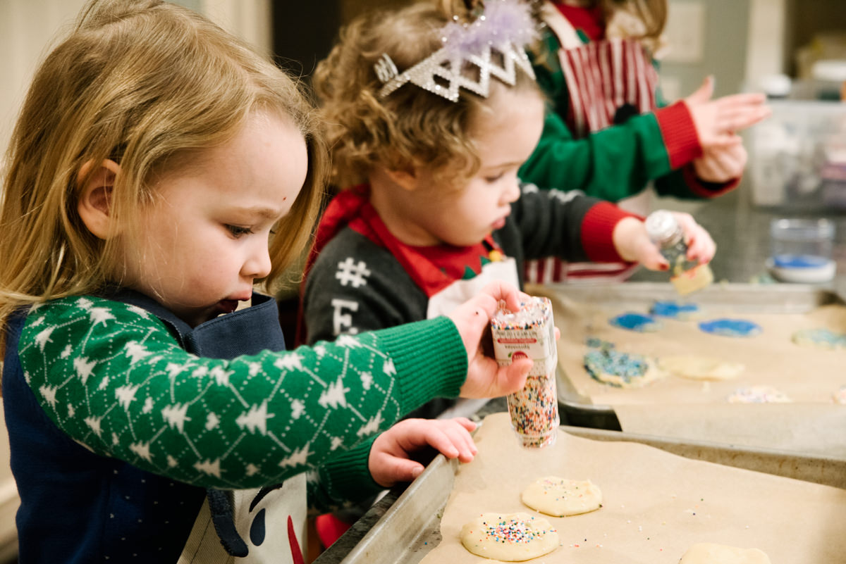 Children put sprinkles on cookies.