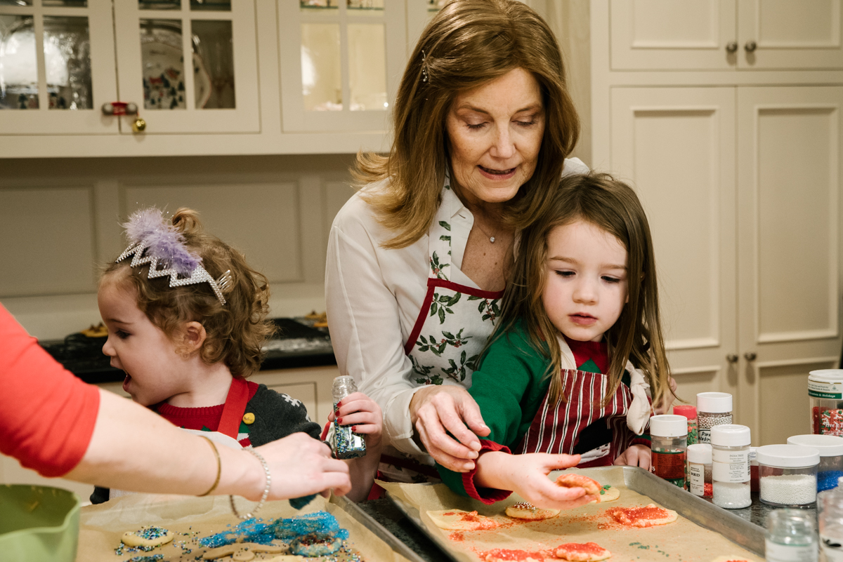 Grandmother helps grandson put sprinkles on holiday cookies.