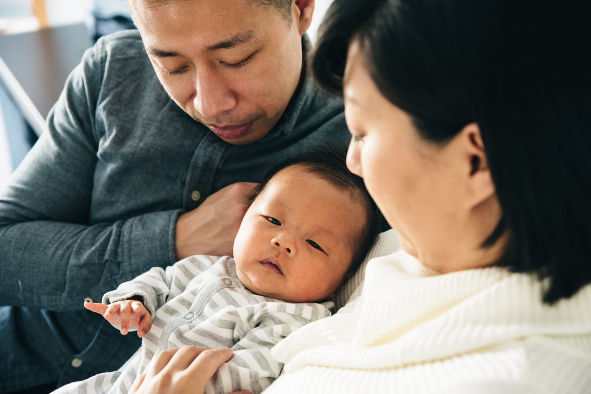 Newborn boy in in parents arms. Minnetonka in-home photography.