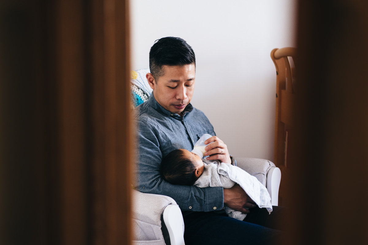 Father feeding baby in rocking chair.