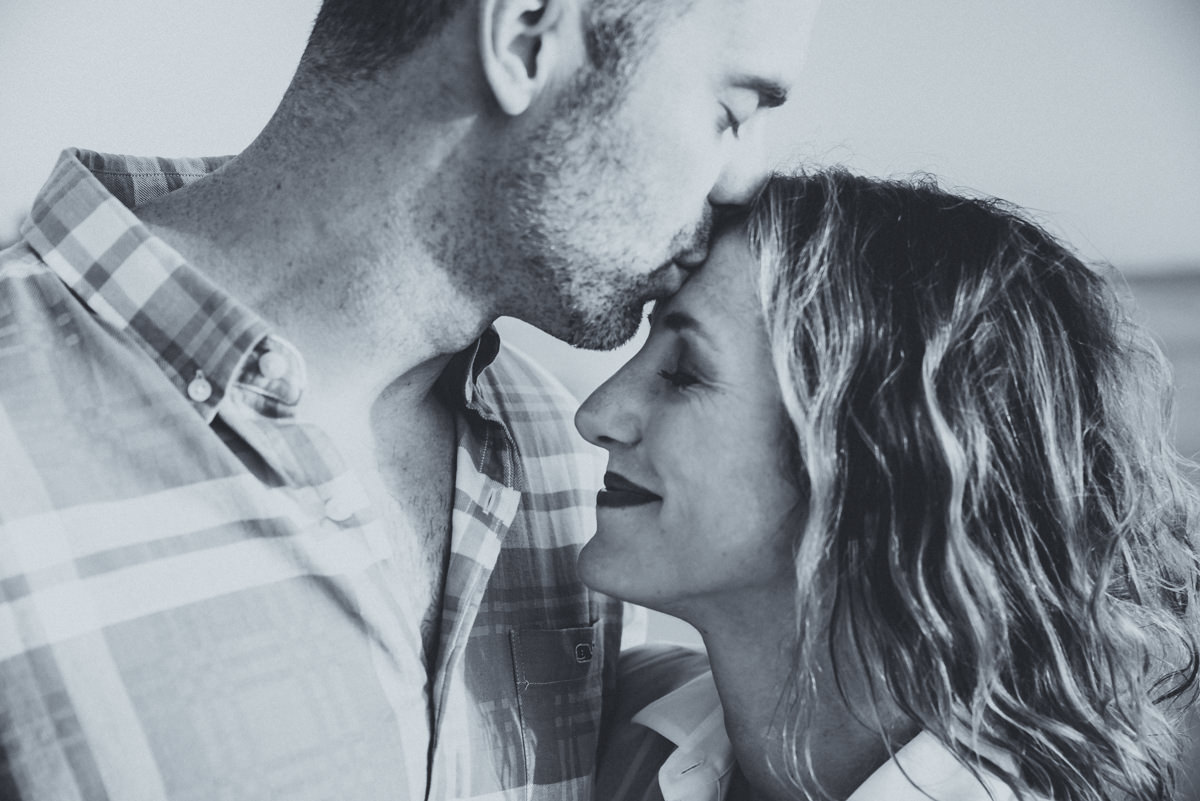 Man kisses woman on the head on the beach. 