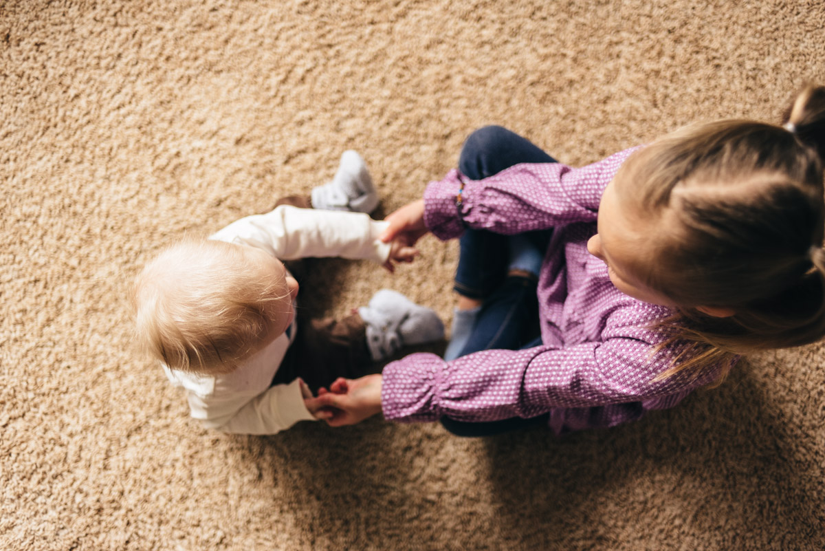 sister and brother playing on carpet. Photo from above.